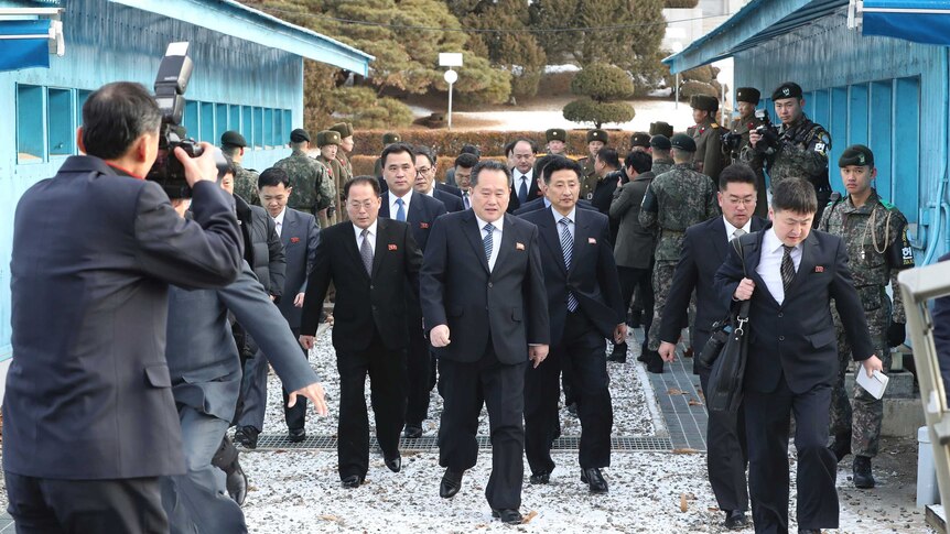 The North Korean delegation arrives. They wear almost identical black suits, ties and what look like DPRK flag pins.