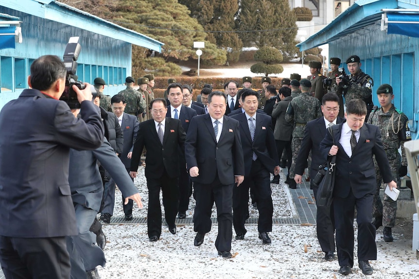 The North Korean delegation arrives. They wear almost identical black suits, ties and what look like DPRK flag pins.