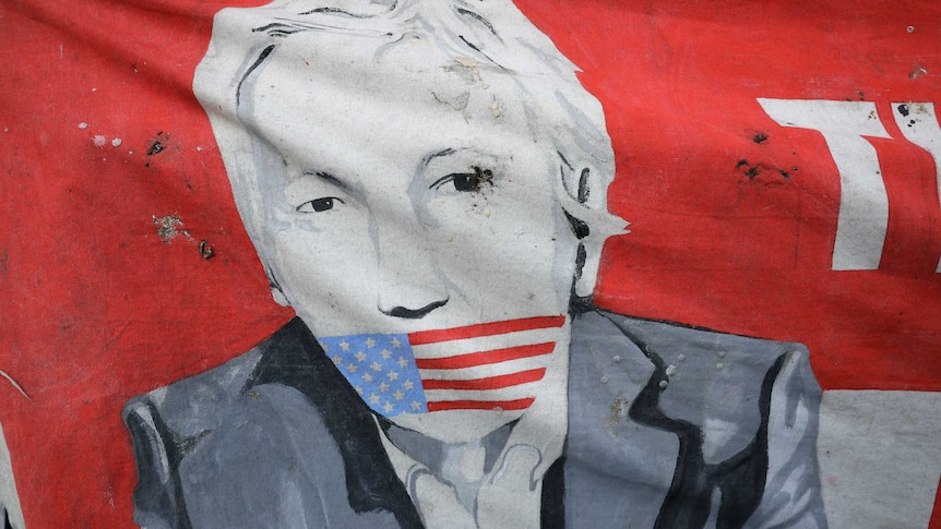 A poster depicts a drawing of Julian Assange gagged by an American flag
