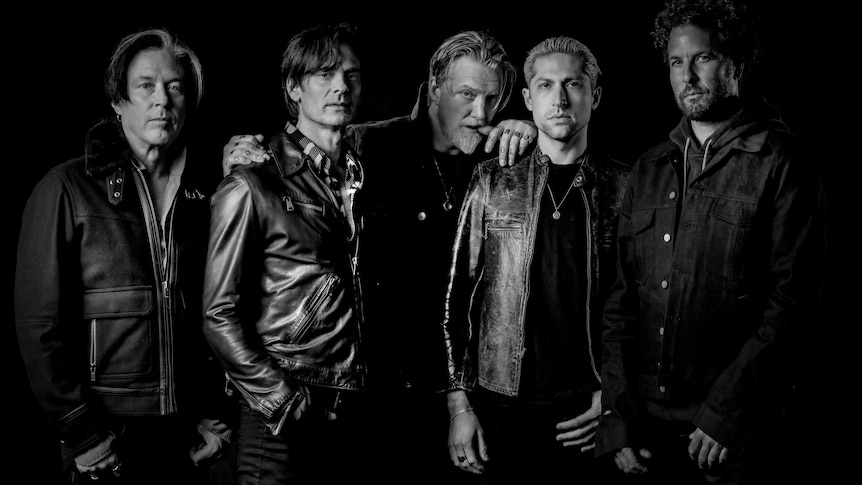 black and white photo of five members of Queens Of The Stone Age standing side by side