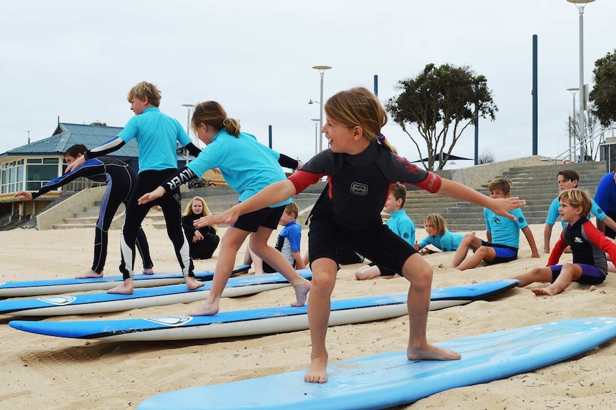 Students practice balancing on boards on the sand.