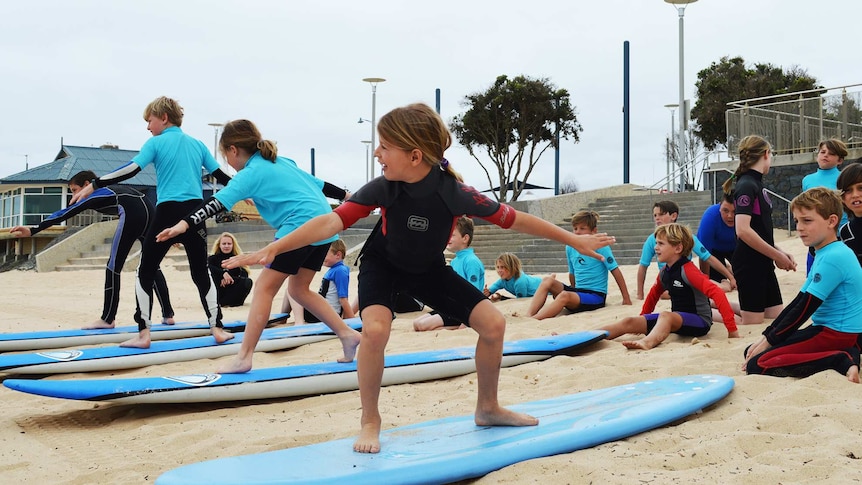 Students practice balancing on boards on the sand.