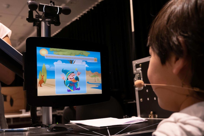 A boy looks at a tablet with an image of a magician