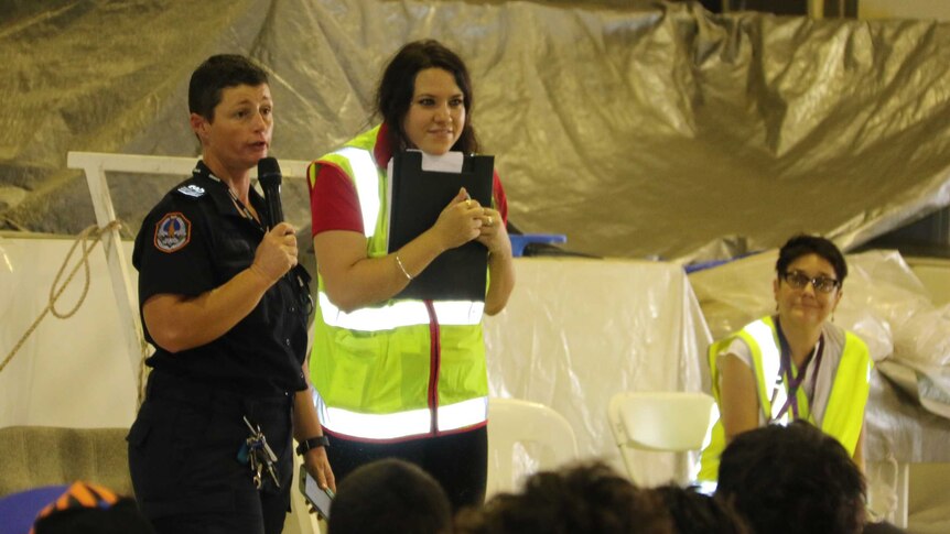 An NT Police officer addresses evacuees from flooded Daly River community at the Darwin evacuation centre.