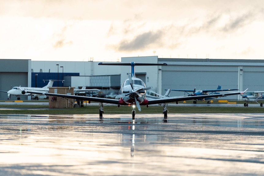 A front-on shot of a Royal Flying Doctor Service plane on the tarmac at Jandakot Airport, preparing to take off.