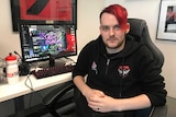Essendon e-Sports player Andrew Rose sits next to a computer on which he plays the game League of Legends