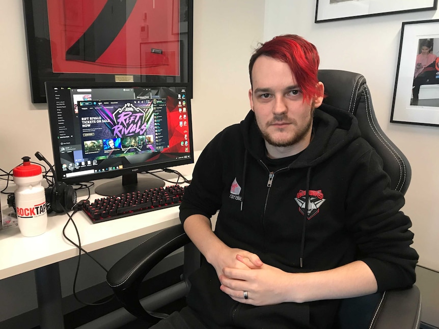 Essendon e-Sports player Andrew Rose sits next to a computer on which he plays the game League of Legends