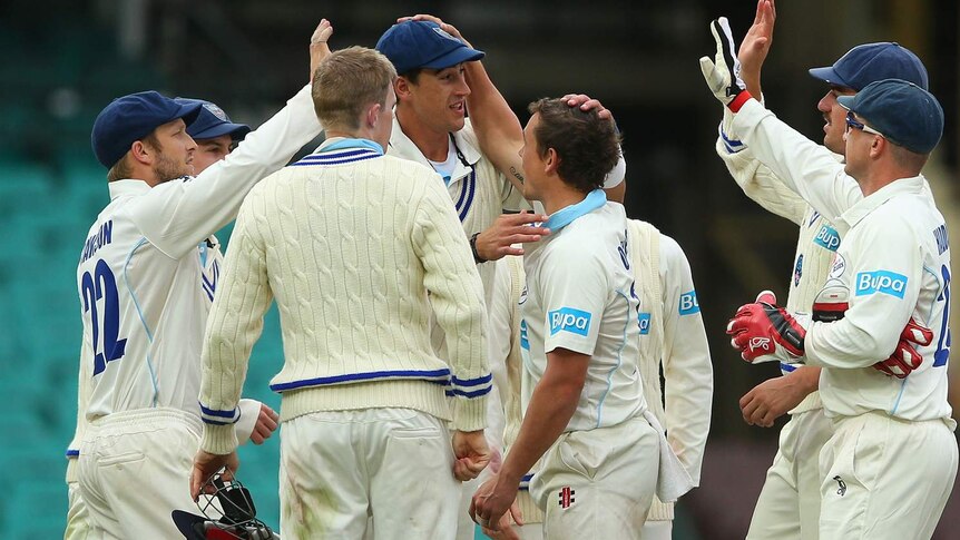 Mitchell Starc is congratulated by team-mates after taking the wicket of Victoria's Glenn Maxwell.