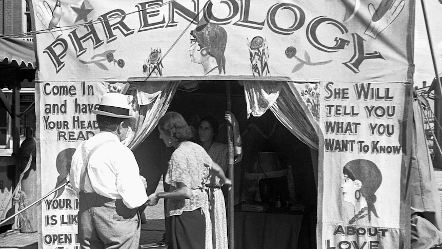 b and w photo of a phrenology tent, with people approaching to enter