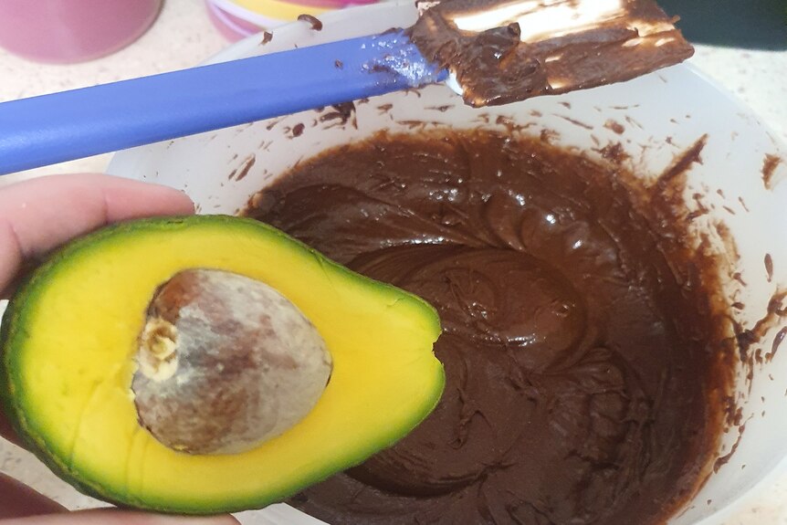 An avocado about to be placed into a mixing bowl.