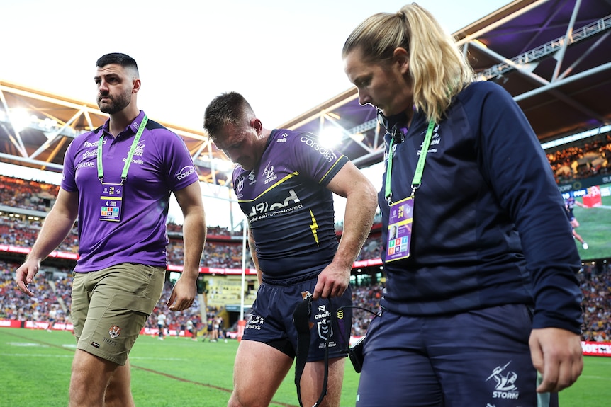 Cameron Munster walks with two of Melbourne Storm's medical staff after being injured during Magic Round.