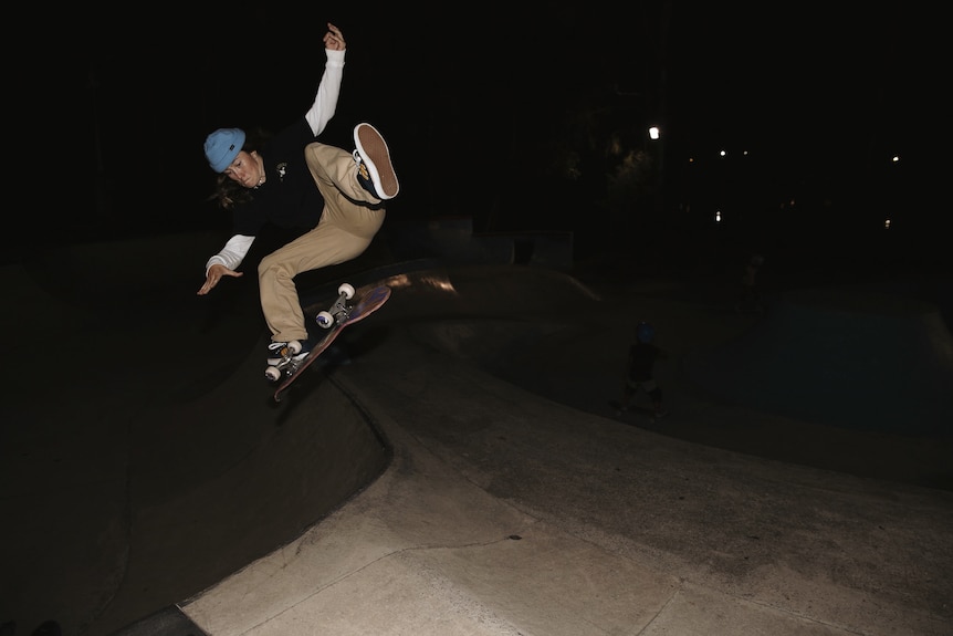 skater flipping their board in mid air at night
