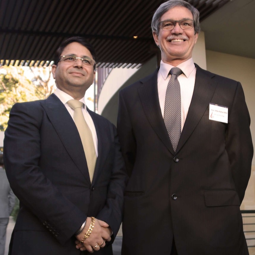 Vikas Rambal and Mike Nahan stand side by side posing for a picture outside a restaurant.