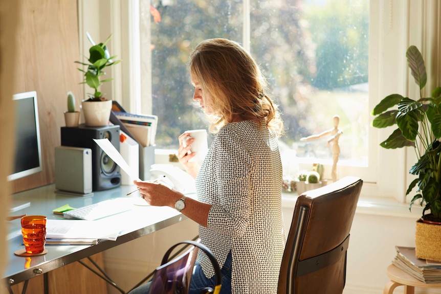 A woman looking at a bill in front of her computer.