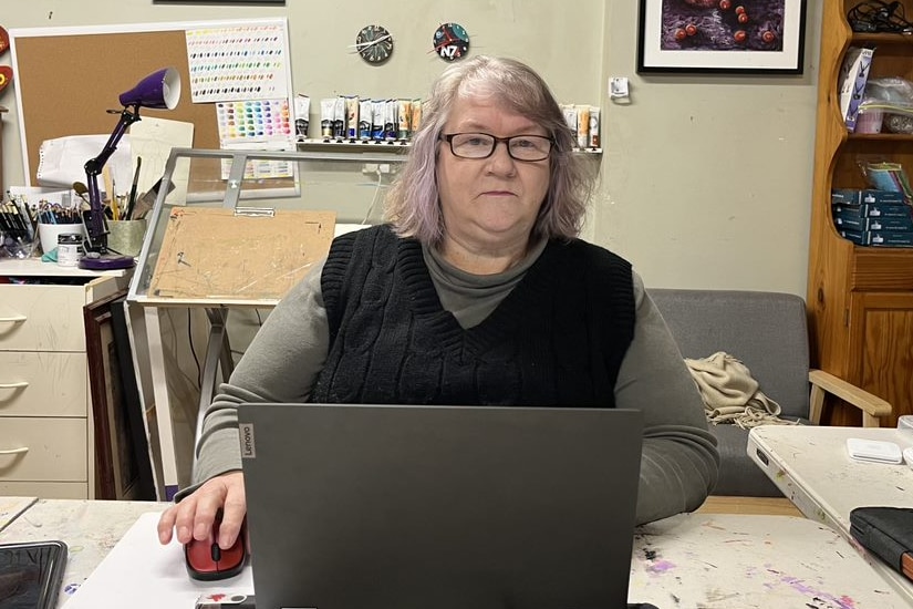 La femme est assise à un bureau avec un ordinateur.