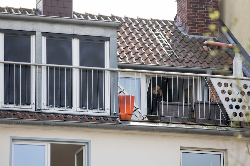 Police search an apartment where the man lived. Officers can be seen through a window.