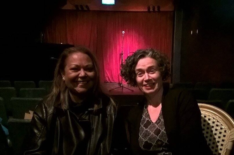 Two women sit smiling in a nightclub