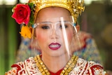 A woman in a Thai traditional outfit wearing a clear face shield