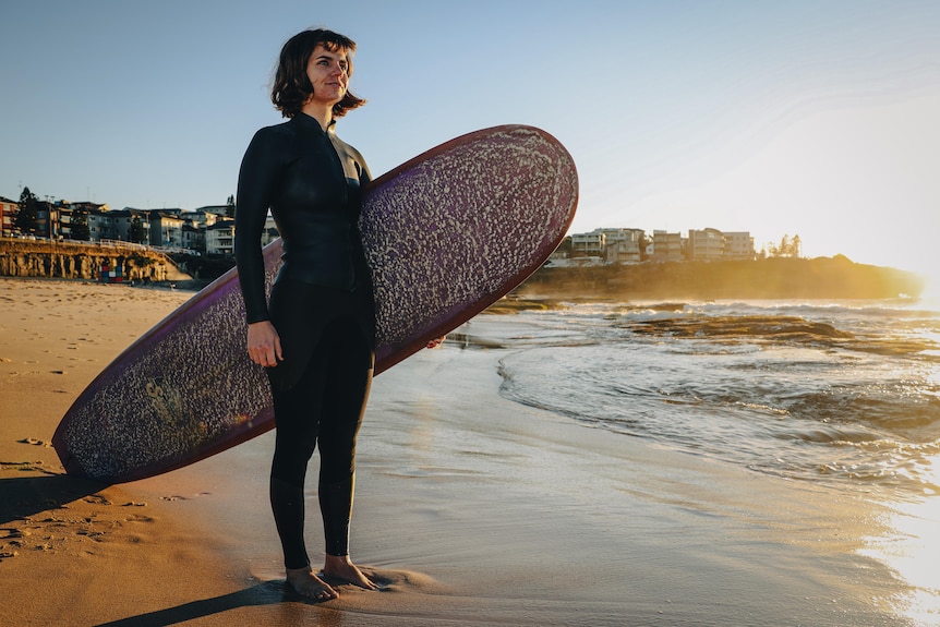 woman standing on a beach at sunrise