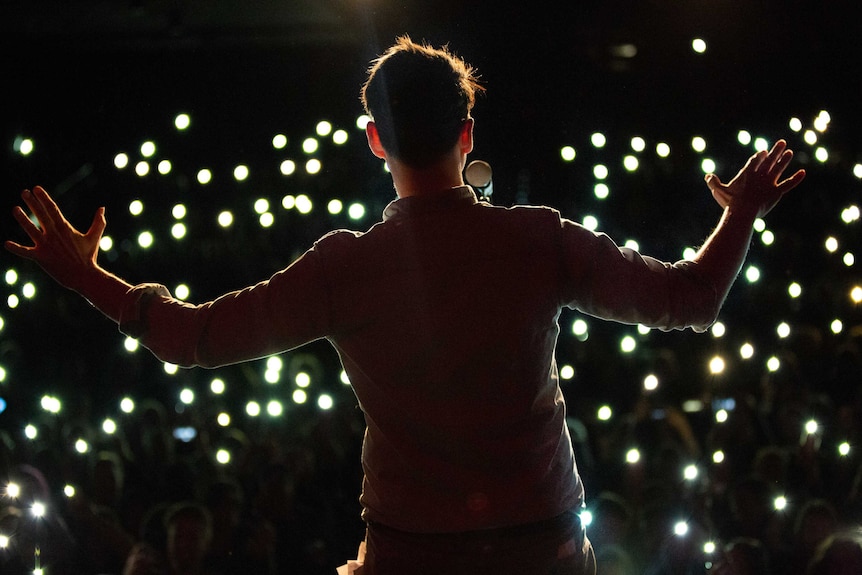 A competitor in front of the lights at The Moth storytelling event in Sydney