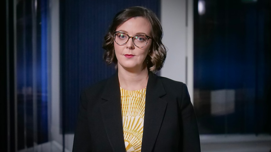 Victoria Engel wearing glasses, a yellow shirt and dark jacket.