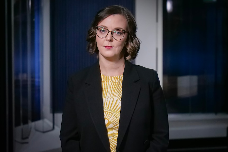 Victoria Engel wearing glasses, a yellow shirt and dark jacket.