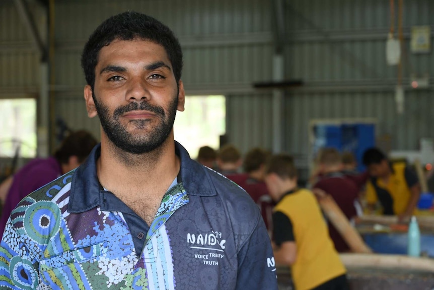 Corey Appo stands wearing an indigenous print shirt in a manual arts shed at Eidsvold State School.