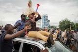 A man blows a child's trumpet toy as he sits the bonnet of a car as people celebrate in the streets in the capital Bamako.