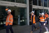 Workers walk past the Reserve Bank of Australia exterior.