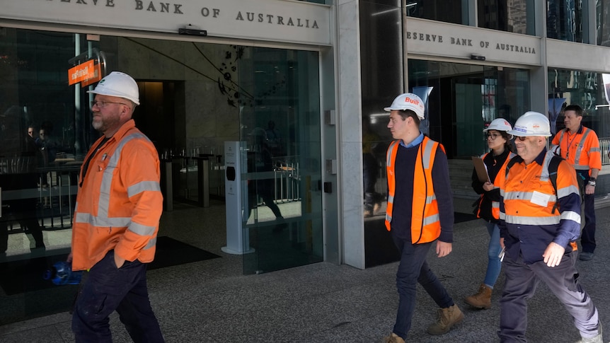 Workers walk past the Reserve Bank of Australia exterior.