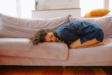 Woman lying in curled up position on couch. 
