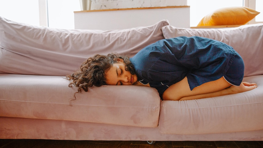 Woman lying in curled up position on couch. 