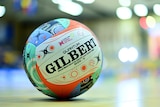 A netball showcasing Indigenous art is photographed on the ground of a netball court