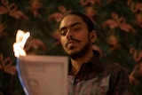 A still from the film The White Tiger with a young man burning a piece of paper