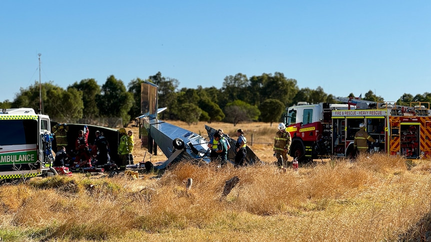 The scene of the plane crash near bunbury, police officers and firefighters inspect the scene and paramedics treat the pilot.