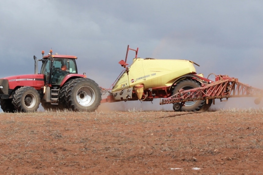 A sprayer towed by a tractor.