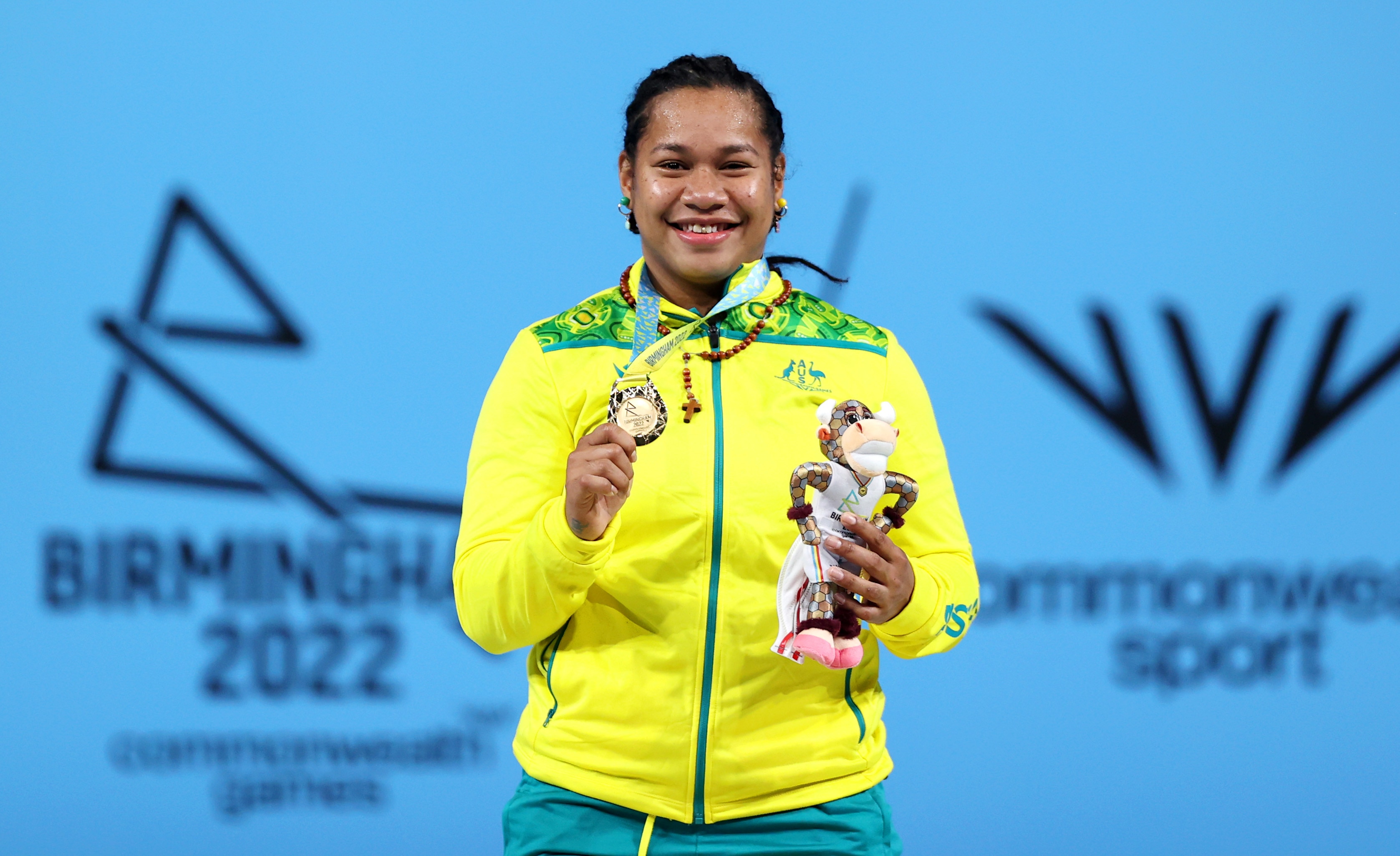 Eileen Cikamatana holds her gold medal and a plushie up for the camera 
