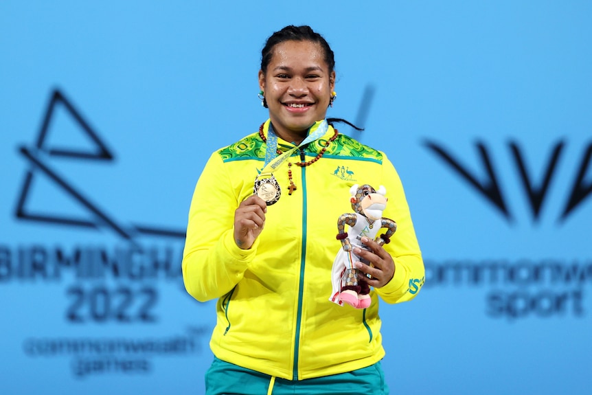 Eileen Cikamatana holds her gold medal and a plushie up for the camera 
