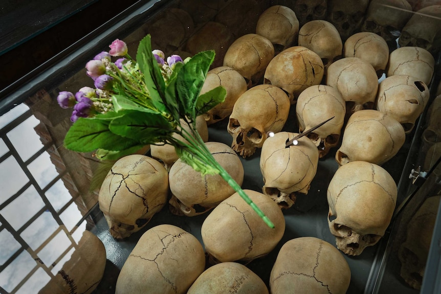 Flowers are laid on top of a glass case containing the skulls of some of those who were slaughtered