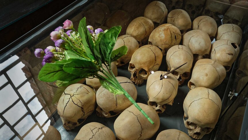 Flowers are laid on top of a glass case containing the skulls of some of those who were slaughtered