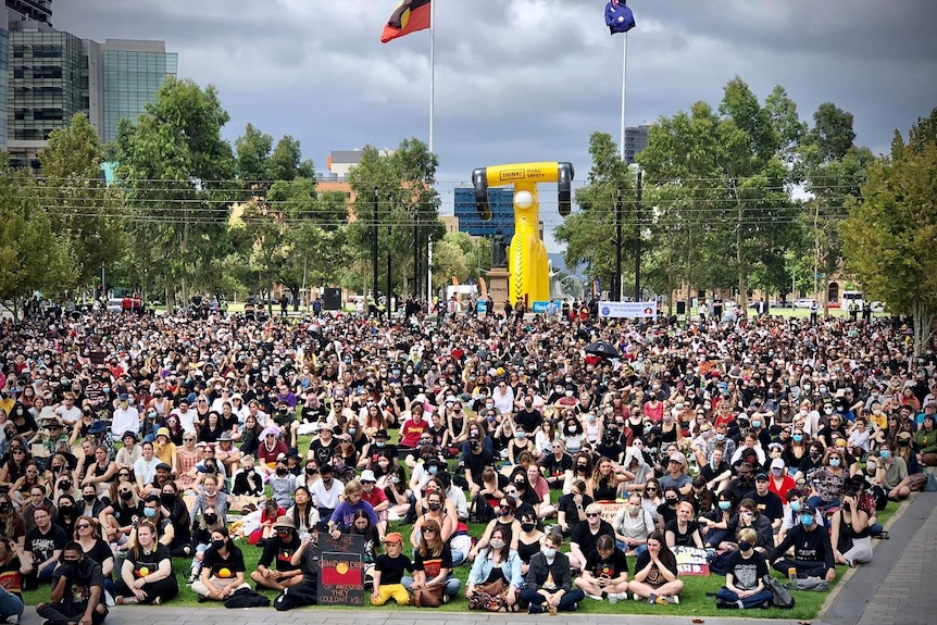 Thousands of masked people sit at an Invasion Day rally in Adelaide.