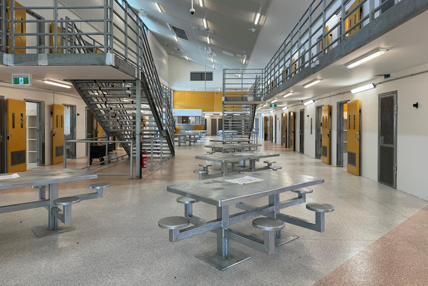 A metal picnic tables in the middle of a room lined with cells with yellow doors