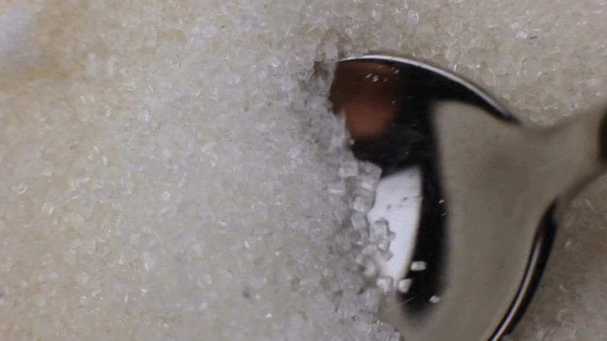 A close-up of a spoon scooping through sugar