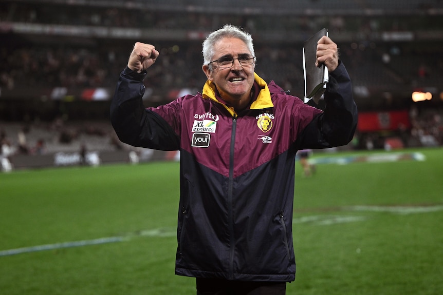 chris fagan holds both fists in the air on the sideline of a football field