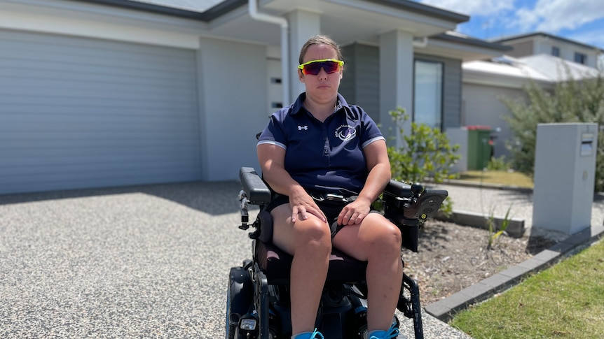 a woman in a wheelchair on the driveway of a home