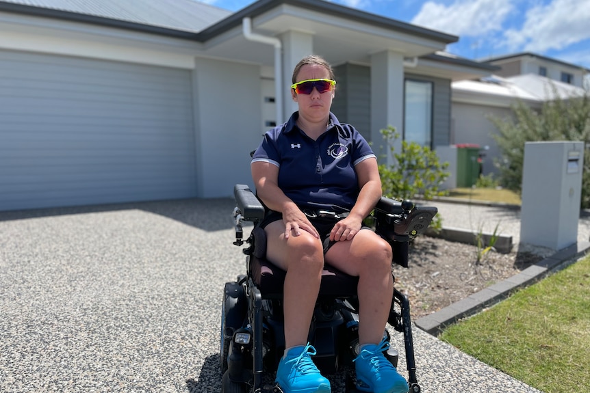 a woman in a wheelchair on the driveway of a home