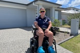 a woman in a wheelchair on the driveway of a home