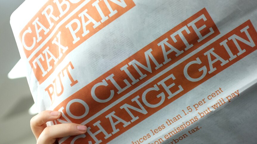 A woman holds the Australian Newspaper showing a full page anti carbon tax ad.