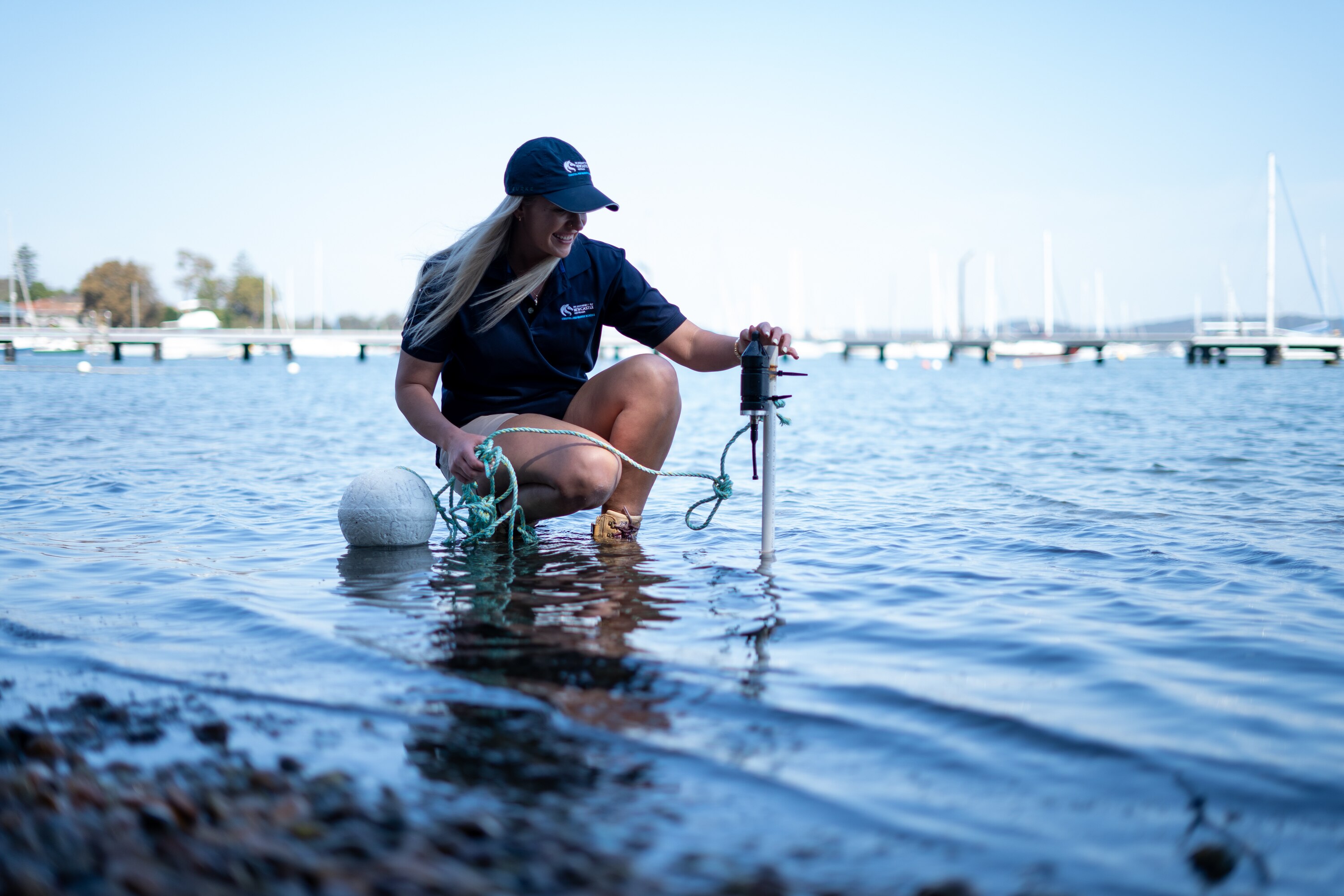 Brittney kneeling at the water's edge with a hydrophone