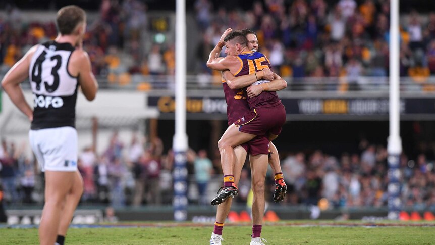 An AFL player jumps into his teammates' arms after they win their game.